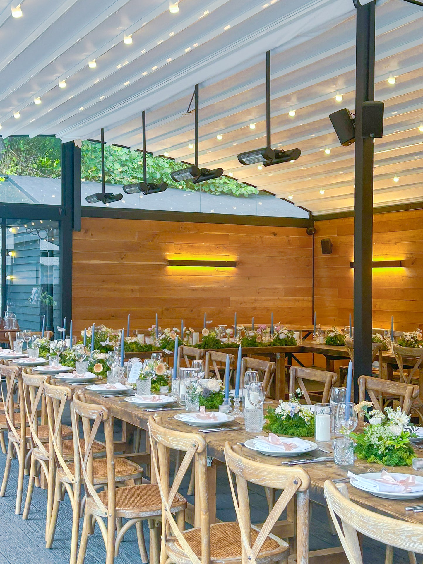 Long dinner table area styled with moss based floral arrangement and various heights of candles