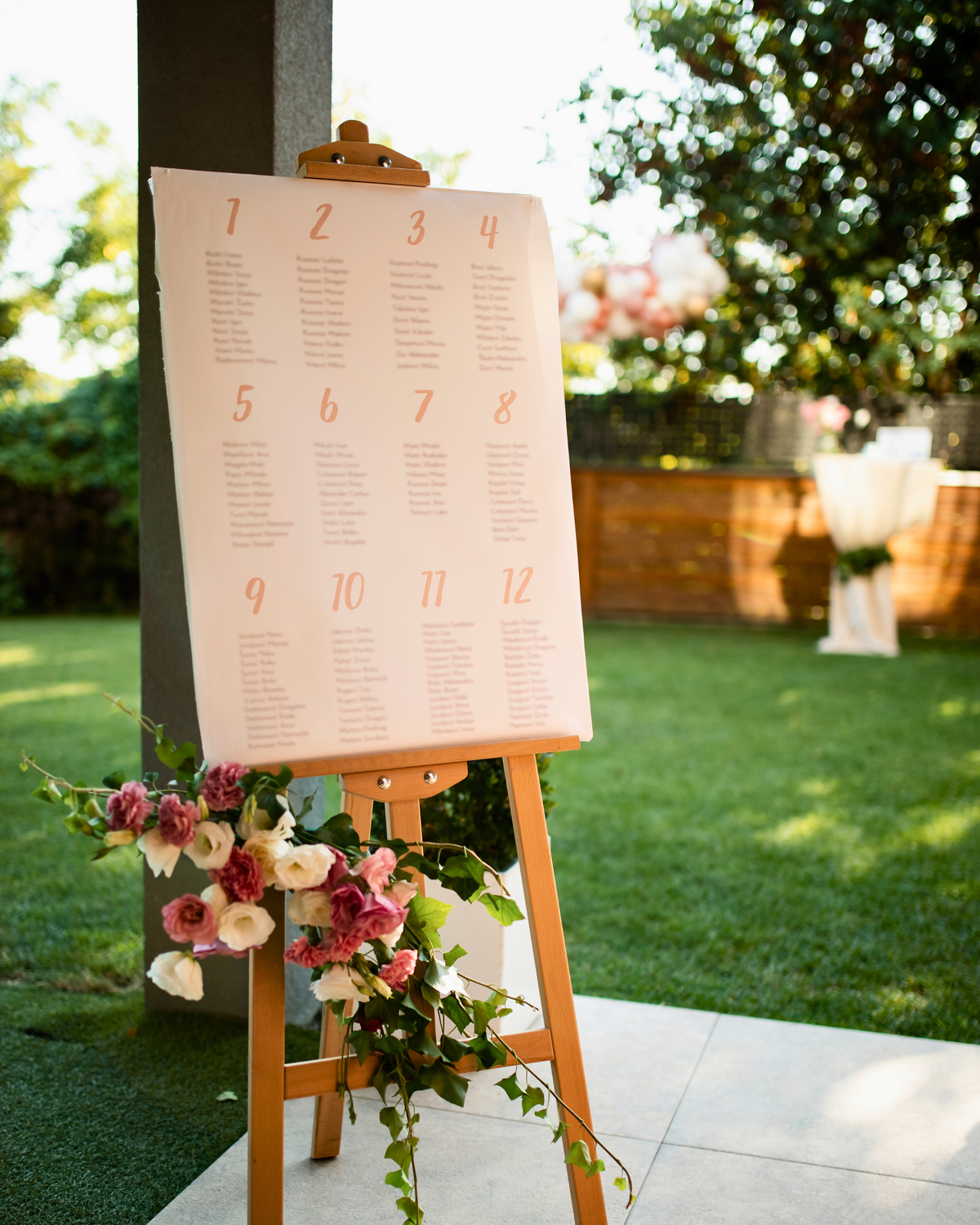 Seating chart on an easel with floral decorations outdoors
