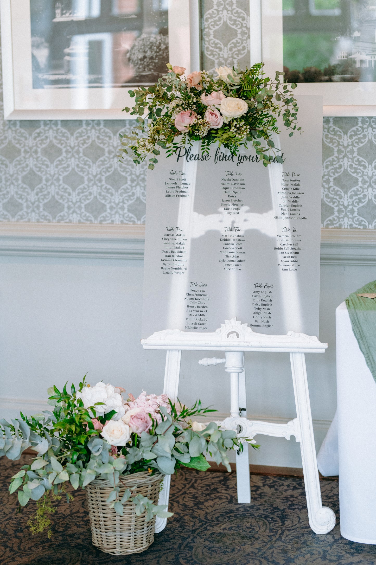 White easel with seating chart and floral decorations.