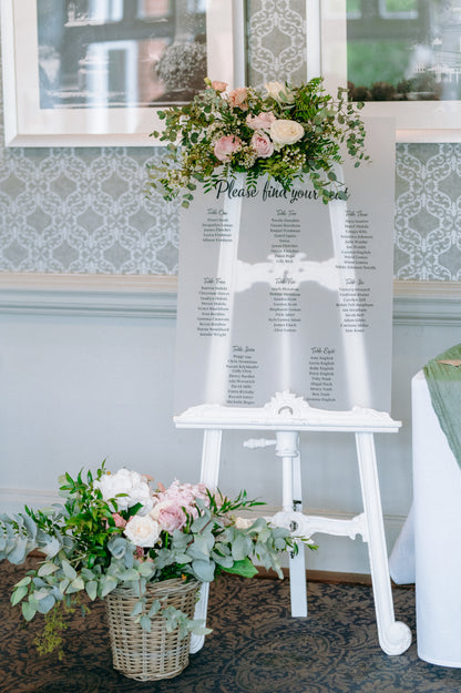 White easel with seating chart and floral decorations.