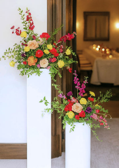 Colourful flowers arranged on a pedestal to welcome guests at an intimate dinner