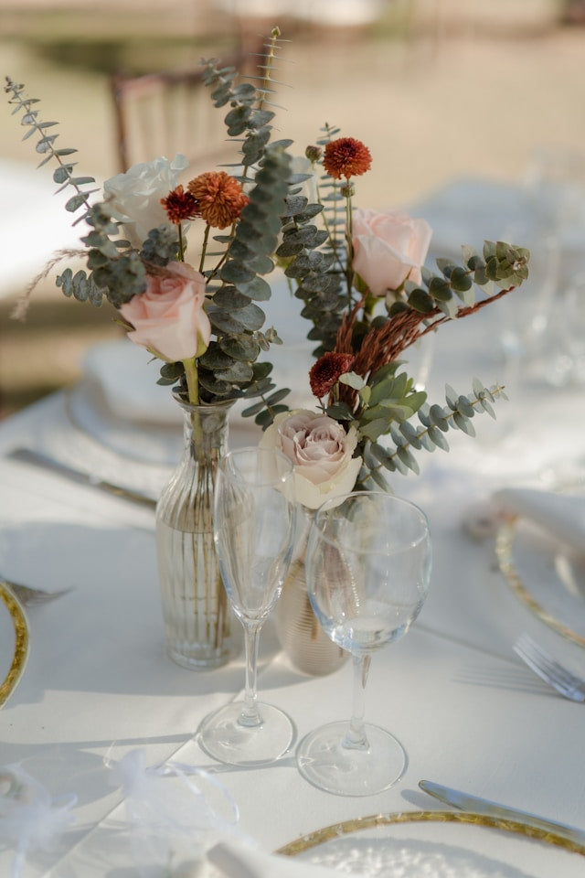 Bud vases with flowers arranged on a table, glass vases, table setting