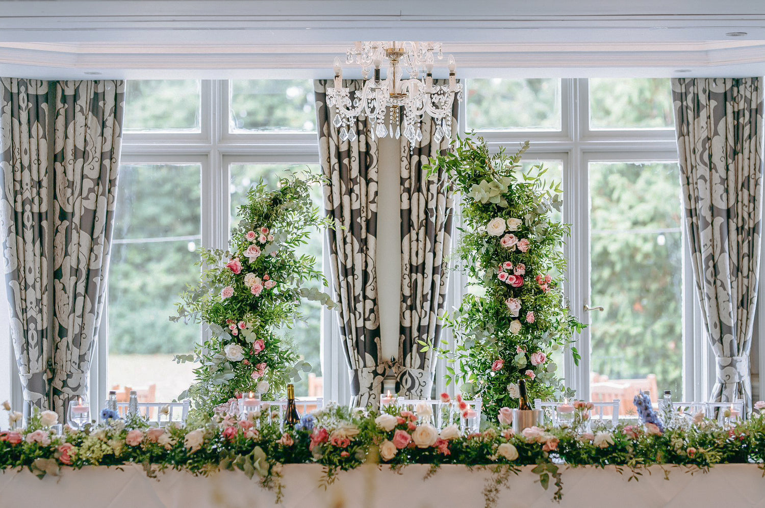 Floral arch decorated with pink and white roses, hydrangeas, carnations, and foliage.