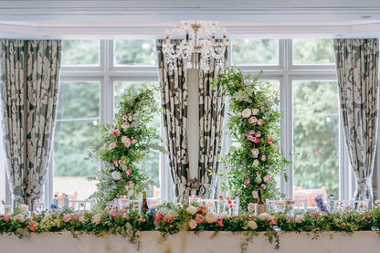 Floral arch decorated with pink and white roses, hydrangeas, carnations, and foliage.