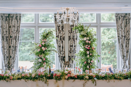 Floral arch decorated with pink and white roses, hydrangeas, carnations, and foliage.
