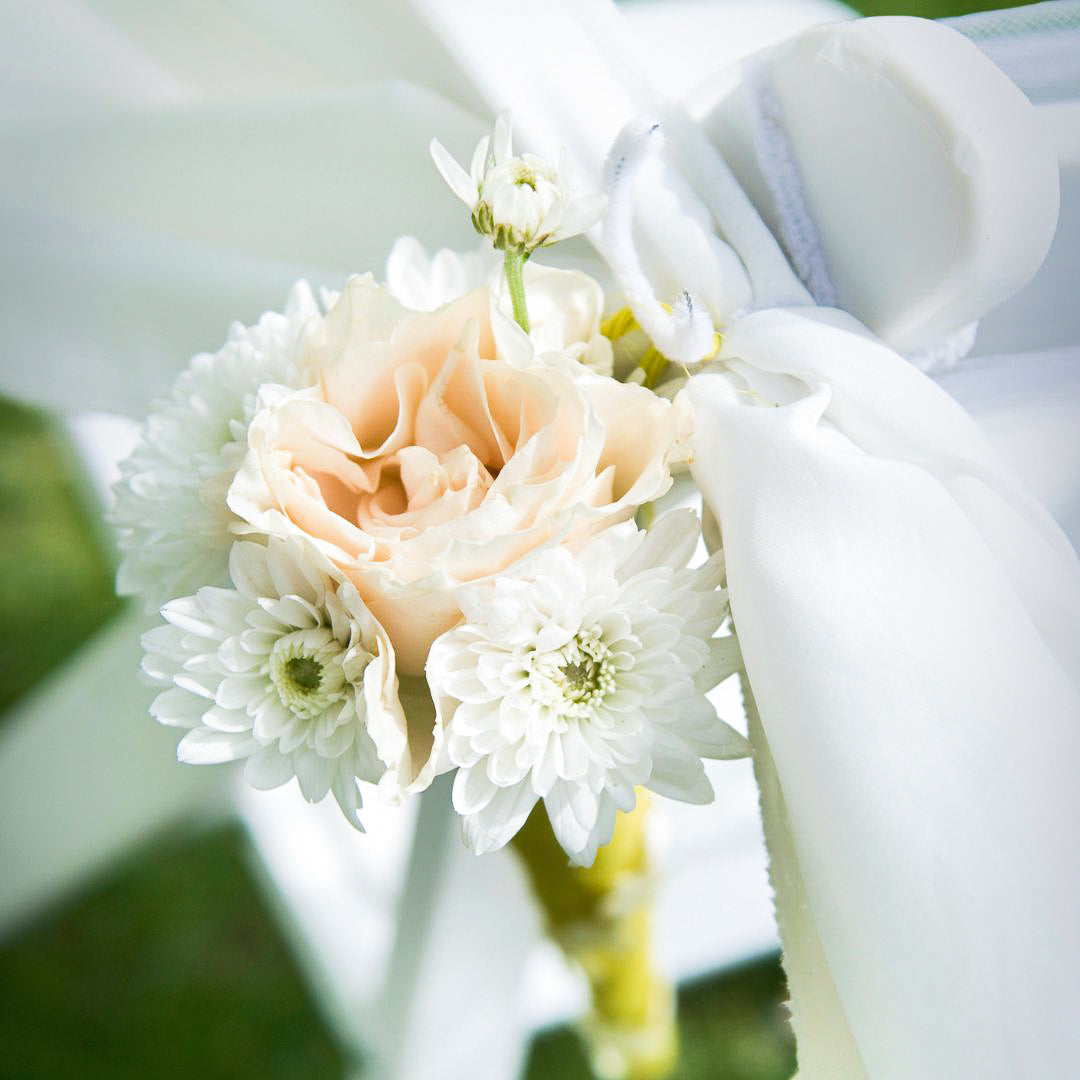 Close-up of a bouquet with white and peach flowers, tied with a white ribbon.