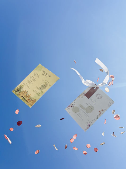 Two menus with ribbons and rose petals against a blue sky